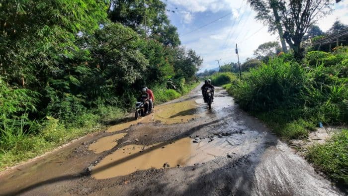 jalan_rusak_parah_menuju_tigaras_kian_memprihatinkan_pengendara_dan_warga_mengeluh_berat