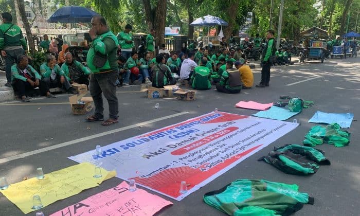 geruduk_dprd_sumut_ratusan_driver_ojol_bentangkan_jaket_aplikasi_di_atas_aspal