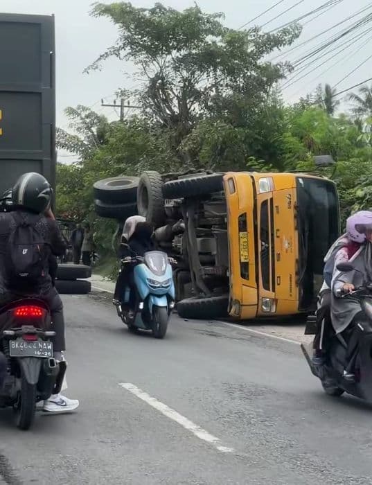 dump_truk_muatan_tanah_terguling_di_perbaungan_patah_as_roda_timpa_motor