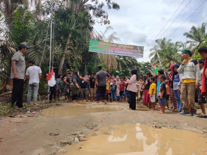 upacara_hari_lahir_pancasila_warga_asahan_pasang_bendera_di_jalan_rusak