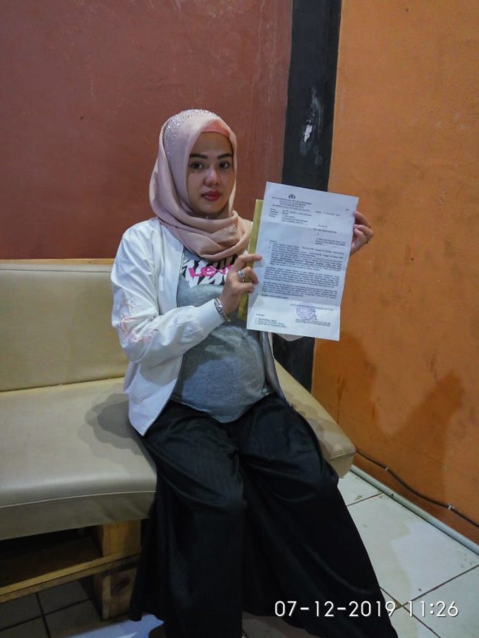 Nanik Mustika yang dalam kondsi hamil tengah memperlihatkan bukti laporan pengadduannya. (f:hendra/mistar