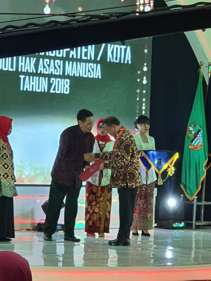 Dirjen Hak Asasi Manusia Mualimin Abdi SH MH menyerahkan penghargaan kepada Bupati Deli Serdang H Ashari Tambunan pada puncak peringatan Hari HAM se dunia ke-71 di Gedung Merdeka Bandung Jawa Barat,Selasa (10/12). (mistar/istimewa)