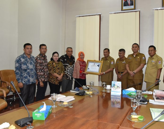 Ketua KPU Deli Serdang Timo Dahlia Daulay menyerahkan penghargaan kepada Bupati Deli Serdang H Ashari Tambunan. (f:ist/mistar)