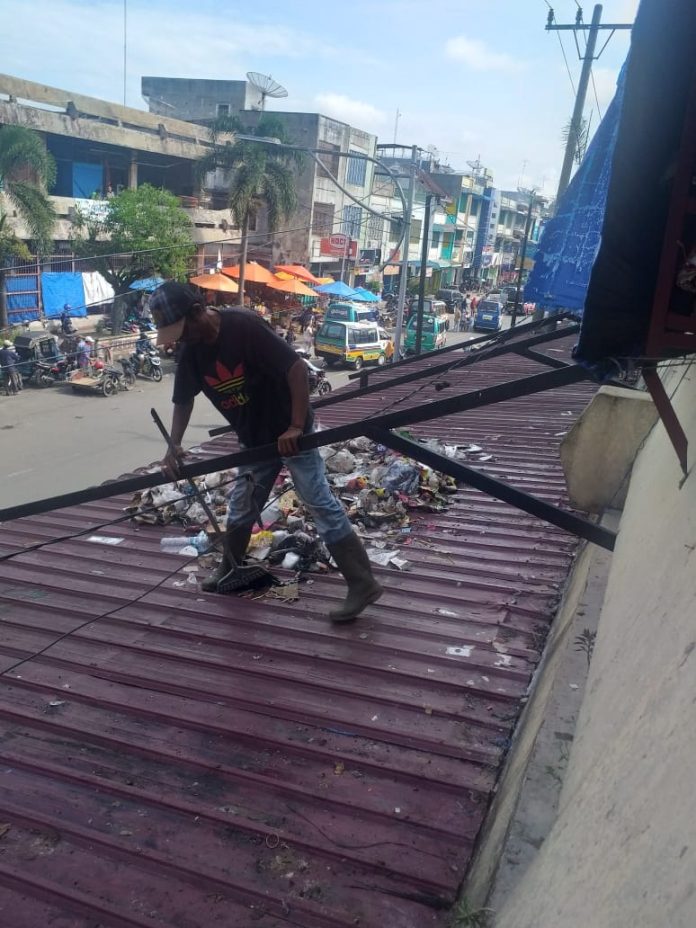 Petugas kebersihan membersihkan sampah yang berserak di kanopi (atap) Pasar Horas, Kamis (30/1/20) sekitar pukul 09.00 Wib.(f:mistar/yetty)