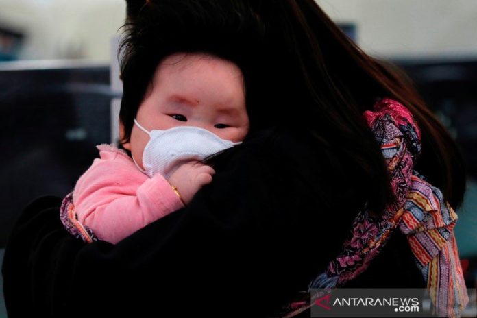 Seorang bayi memakai masker untuk mencegah penularan virus korona baru di Stasiun Kereta Cepat Hong Kong West Kowloon di Hong Kong, China, Kamis (23/1/2020). REUTERS./Tyrone Siu/wsj/cfo