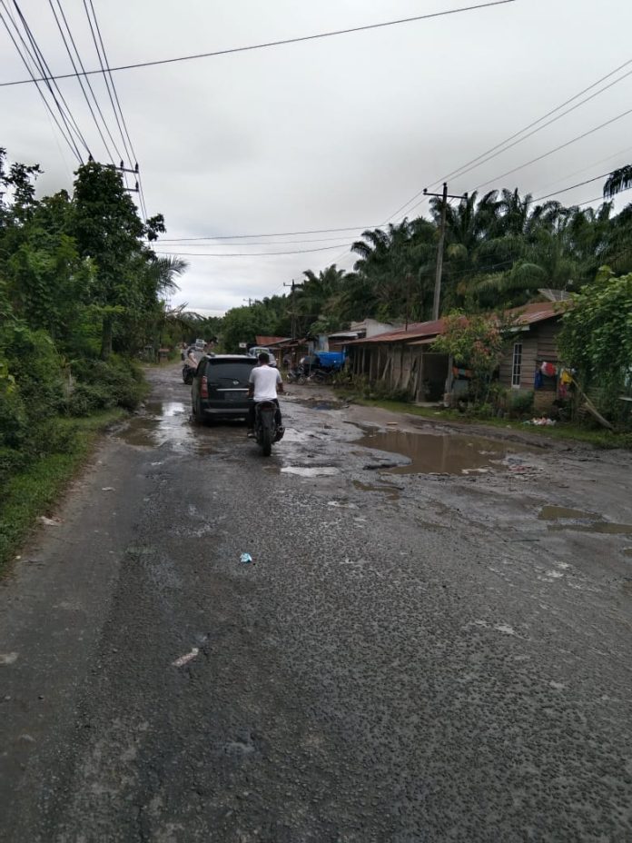 Kendaraan minibus sedang melintas di jalan yang rusak parah dan berlubang dan digenangi air di Kawasan Kedai Panjang Kelurahan Pematang Tanah Jawa,Kabupaten Simalungun. (f:ist/mistar)