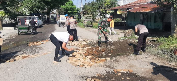 Polsek dan Koramil Pantai Cermin Lakukan Penimbunan Jalan Provinsi yang Berlubang