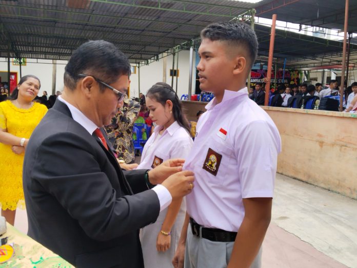 Hotlion Sihombing (Jas hitam) mencopot seragam sekolah secara simbolik pada salah seorang siswa di Wisuda Purnawiyata siswa-siswi kelas XII TP 2022-2023. (f:Yetty/mistar)