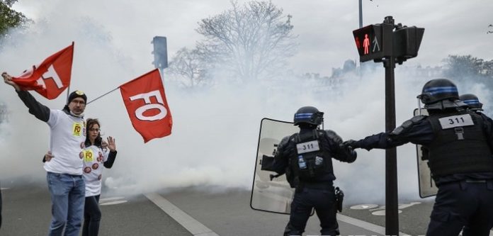 Para pengunjuk rasa mengibarkan bendera serikat buruh Force Ouvriere (FO) di samping polisi anti huru hara selama unjuk rasa menentang reformasi pensiun pemerintah di Paris, Prancis, Selasa (28/3/2023) (f;republika/mistar)