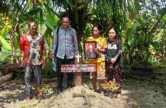 Rosmaida (baju kuning) saat berada di makam suaminya bersama pengacara Eljones Simanjuntak.