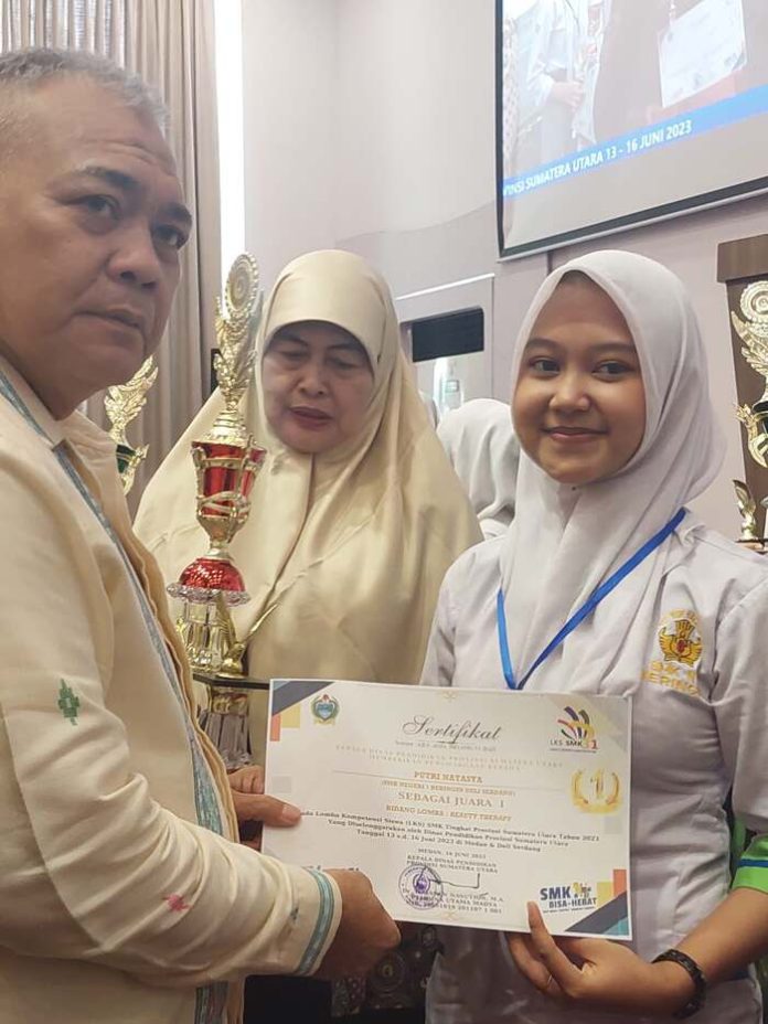 Kepala Dinas Pendidikan Provinsi Sumatera Utara Sumatera,DR.H.Asren Nasution menyerahkan tropi dan piagam penghargaan kepada siswa SMKN 1 Beringin,Putri Natasya didampingi kepala sekolahnya Hafrida Hanum di Hotel Wing (f;rinaldi/mistar)