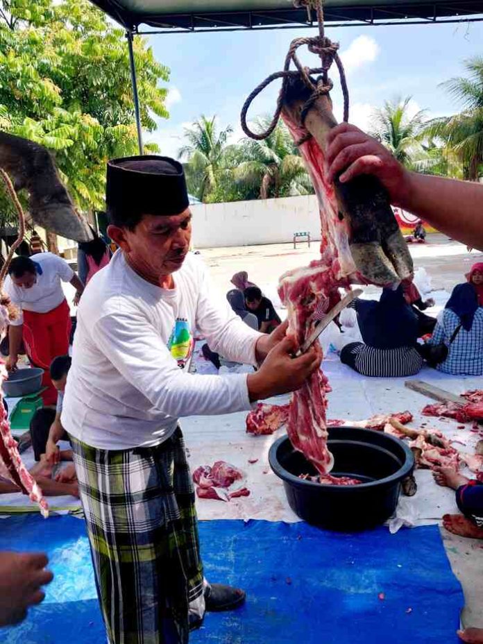 H.Misinun Moris bersama guru dan pegawai ikut memotong daging pada potongan hewan kurban di SMAN 1 Lubuk Pakam (f:rinaldi/mistar)