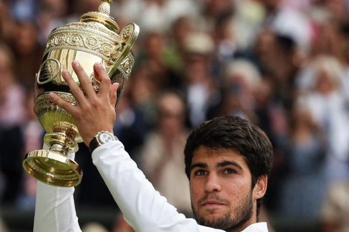 Carlos Alcaraz mengangkat tropi Wimbledon 2023.