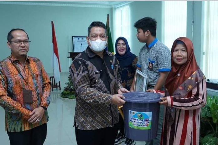 Syarmadani didampingi Kadis Lingkungan Hidup Hasbie Ashhiddiqi memberikan tong sampah kepada seorang warga secara simbolis