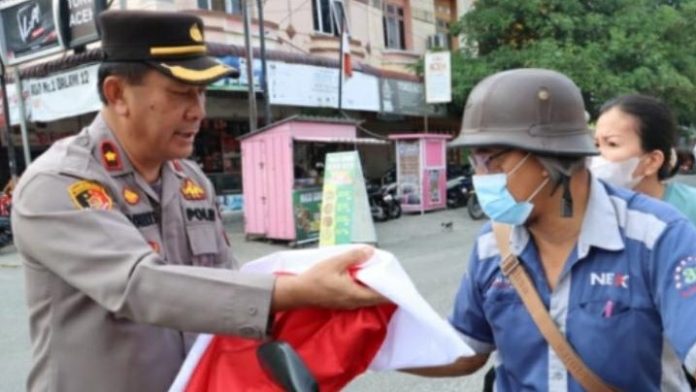 Waka Polres Tebing Tinggi Kompol Asrul Robert Sembiring saat membagikan Bendera Merah Putih.