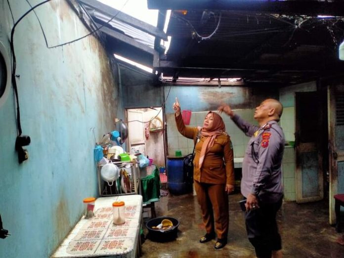 Kapolsek Serbelawan, AKP Yunus Siregar saat memeriksa Rumah warga yang rusak akibat puting beliung bersama Camat Tapian Dolok.(f:ist/mistar)