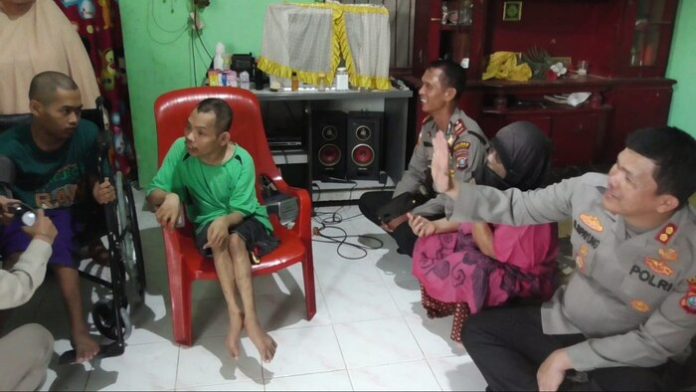 Kapolres Simalungun, AKBP Ronald Sipayung saat mengunjungi satu keluarga yang menderita lumpuh layu.(f:ist/mistar)