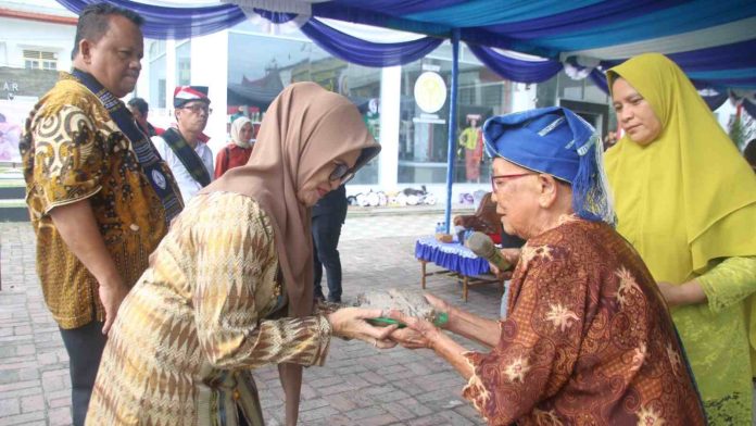 Pembina Sanggar Rayantara Raminah Garingging memberikan Dayok Binatur kepada Susanti dan Erizal Ginting.