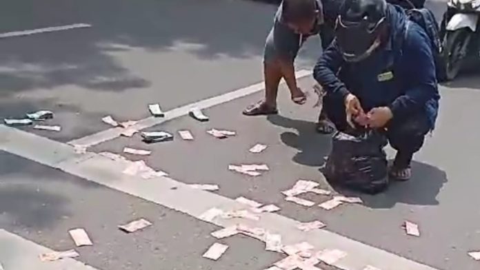 Pemilik dibantu warga memunguti uang yang berserakan di Medan.