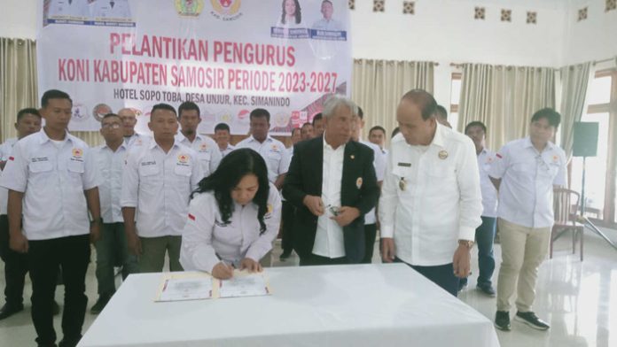 Ketua KONI Samosir,  Rismawati Simarmata menandatangani berita acara pelantikan pengurus KONI Kabupaten Samosir yang disaksikan  Wakil Bupati Samosir Martua Sitanggang. (f:ist/mistar)