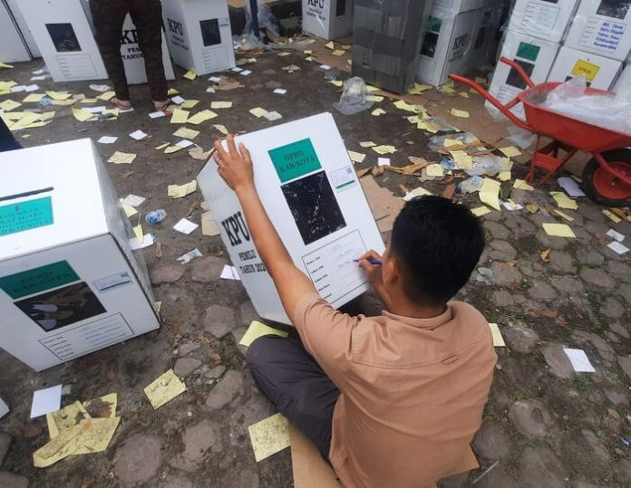 Seorang petugas PPK sedang menulis nomor dan lokasi TPS di kotak suara yang berisi logistik Pemilu sebelum didistribusikan KPU Simalungun.(f:indra/mistar)