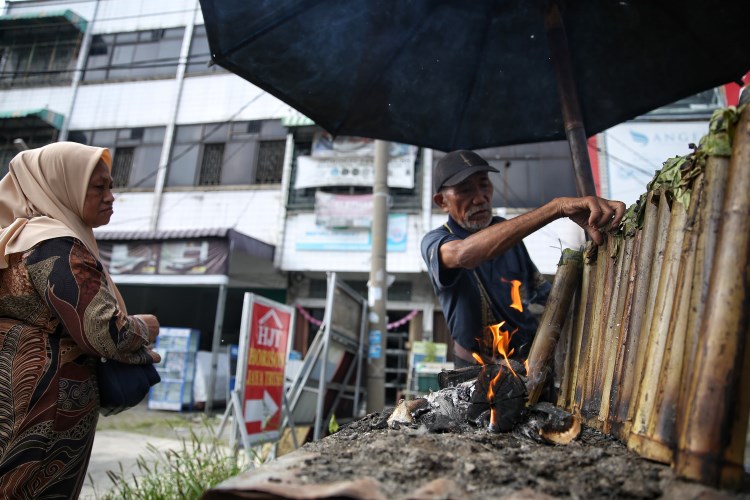 Pedagang lemang menyusun bambu berisi lemang di atas panggangan