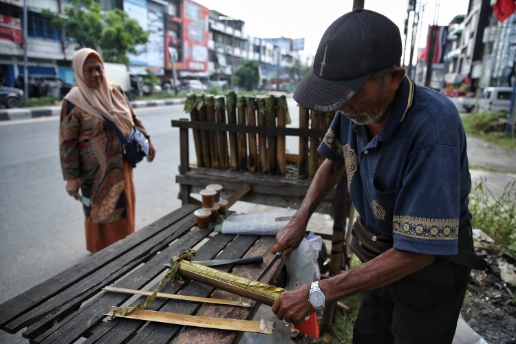 Proses pemotongan lemang setelah dikeluarkan dari bambu