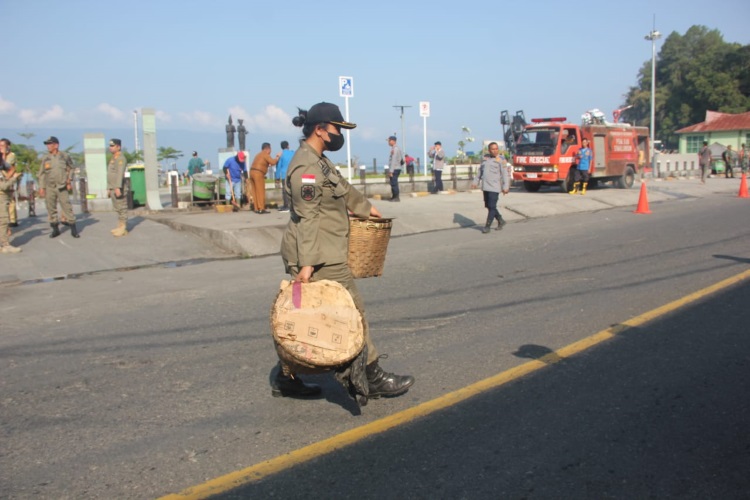 Seorang wanita personil Satpol PP Pemkab Simalungun membantu pedagang mengangkat barang dagangannya