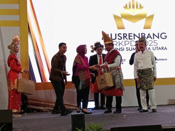 Pj Gubernur Sumut Hassanudin memberi cindera mata usai membuka Musrenbang RKPD 2025 Sumut di Hotel Santika, Medan. (f:hutajulu/mistar)