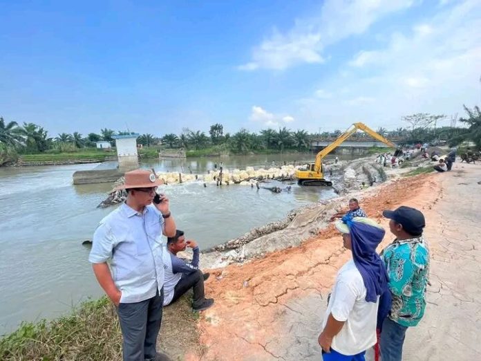 Masyarakat 4 Desa bergotong royong dibantu escavator membendung sungai Dalu Dalu agar air masuk ke sawah mereka. (f : ist/mistar)