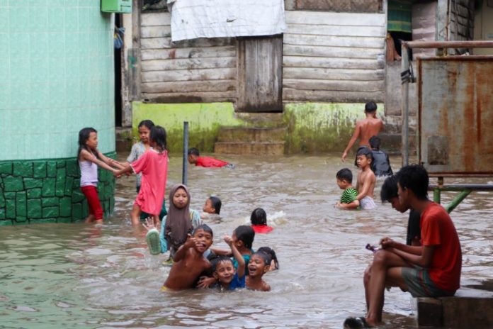 Anak-anak bermain saat banjir melanda Kampung Aur, Kota Medan