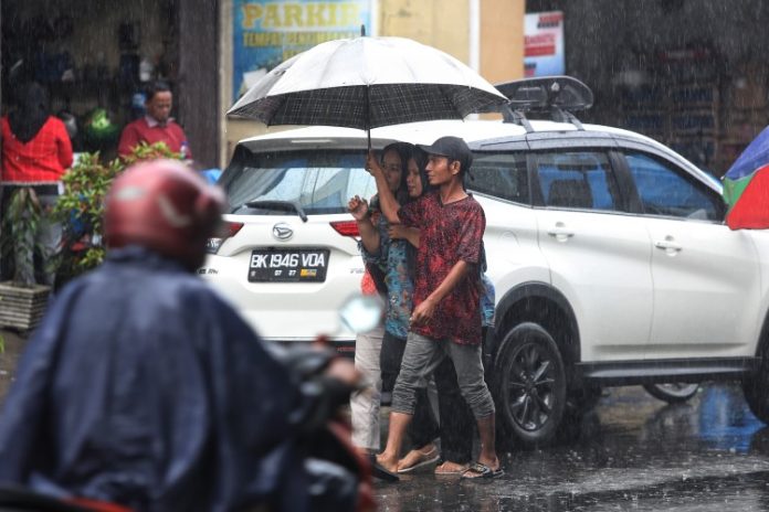 Joki ojek payung sedang melayani pelanggan di Medan