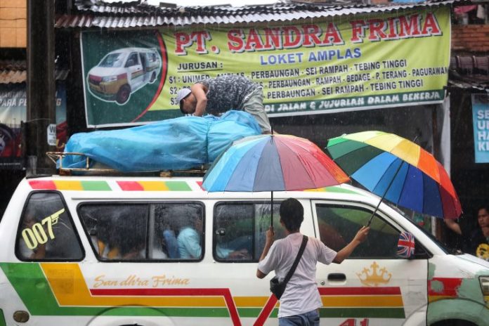 Ojek Payung mencari rezeki di saat hujan mengguyur Kota Medan