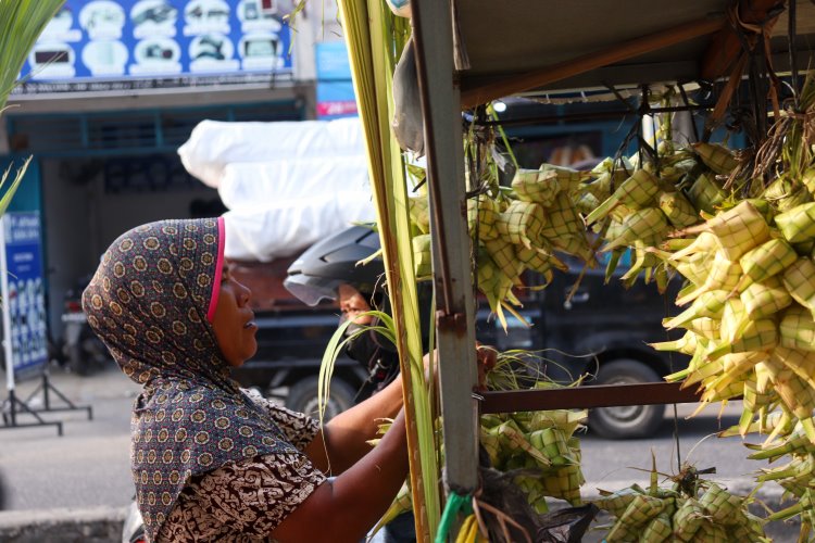 Pedagang sarang ketupat musiman tengah merapikan dagangannya