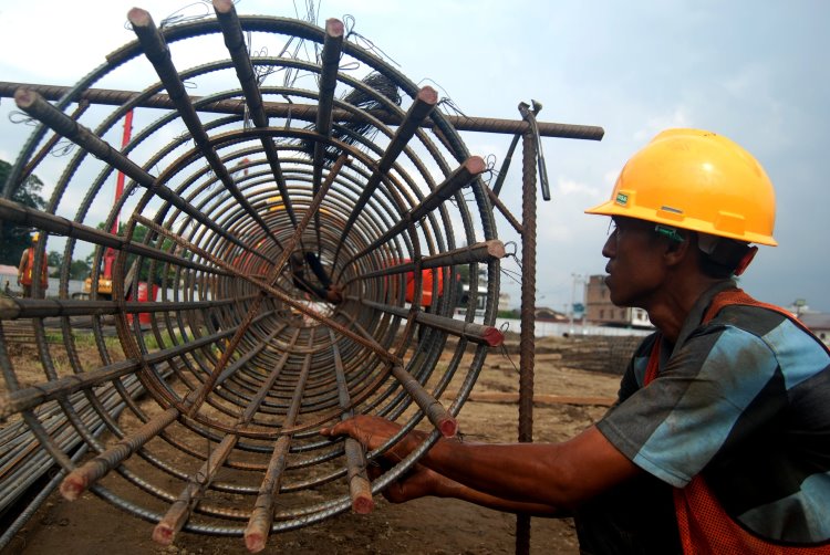 Pekerja konstruksi sedang menyatukan besi ulir menggunakan kawat dalam pembangunan stadion Teladan Medan
