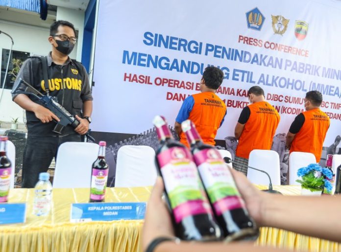 Petugas Bea Cukai memperlihatkan dua dari ribuan botol minuman keras ilegal dengan pita cukai bekas di Medan