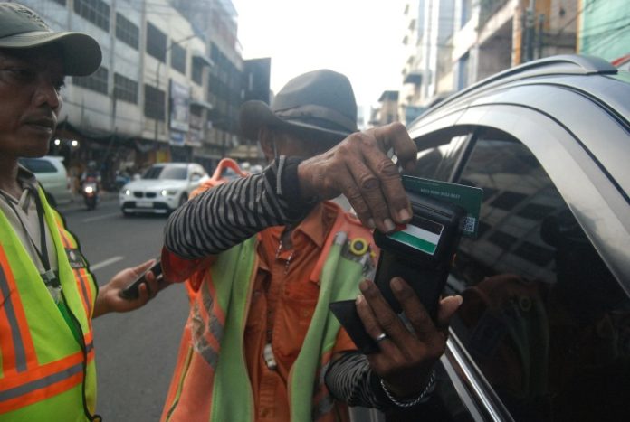 Petugas parkir di Medan sedang menempelkan kartu pembayaran E-Parking milik pengendara