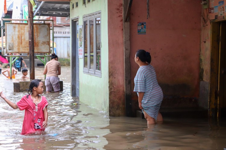 Seorang ibu memanggil anaknya yang tengah bermain kala banjir merendam Kampung Aur