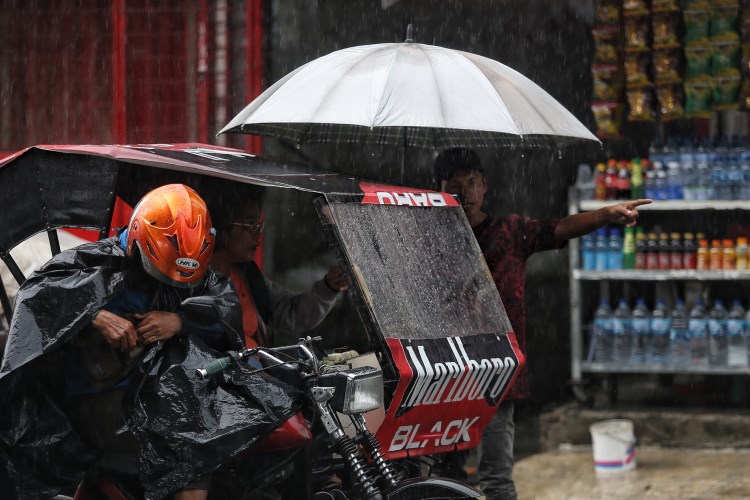 Seorang ojek payung menawarkan jasanya kepada penumpang becak motor dikala hujan di seputaran Terminal Amplas Medan