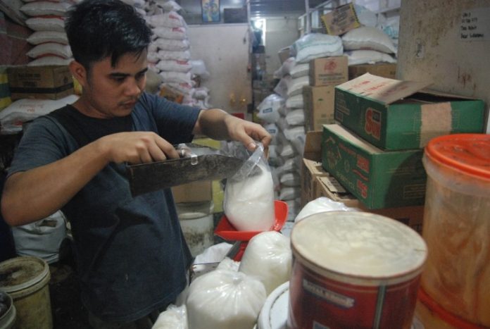 Seorang pekerja toko sembako menimbang gula pasir untuk eceran di Medan