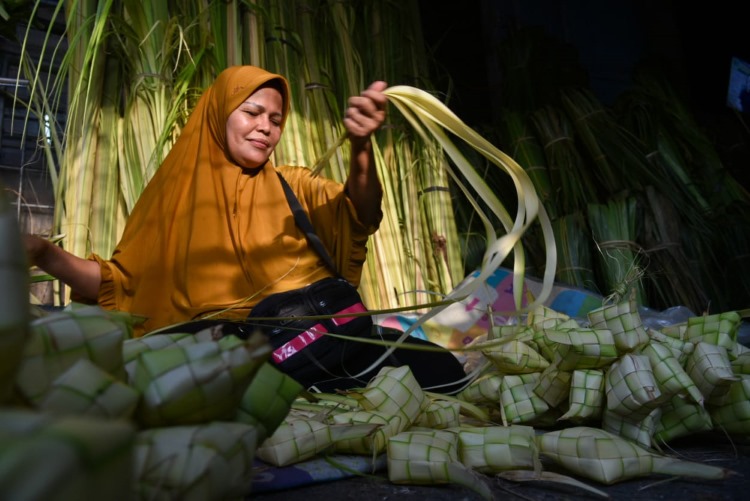 Seorang pengrajin sarang ketupat di Medan sedang menganyam daun kelapa