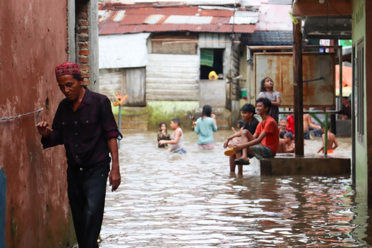 Seorang pria menerjang banjir untuk keluar dari Kampung Aur