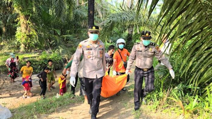 Kapolsek Indrapura AKP Jonni H Damanik (kiri) bersama anggota dan BPBD mengangkat mayat Mr X yang telah dimasukkan kedalam kantong mayat. (f : ist/mistar)