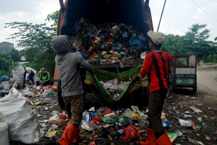 Dua petugas truk sampah sedang bekerja membersihkan sampah di Medan