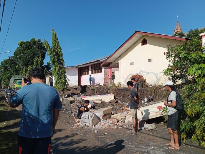 Sejumlah pria menghancurkan reruntuhan tembok SD Negeri 122371 akibat hujan deras.