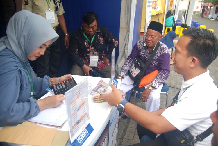 Jamaah calon haji melakukan penukaran uang Riyal di gerai penukaran uang milik BRI di Asrama Haji Medan