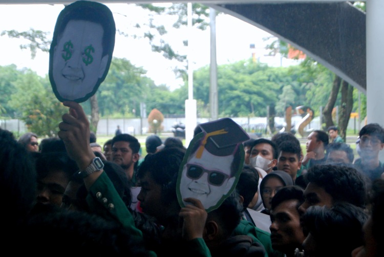 Mahasiswa membawa poster wajah Rektor USU dengan gambar mata uang US Dollar