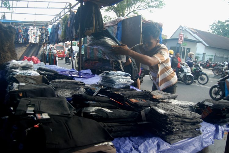 Pedagang pakaian kaki lima di Medan sedang menyusun dagangannya