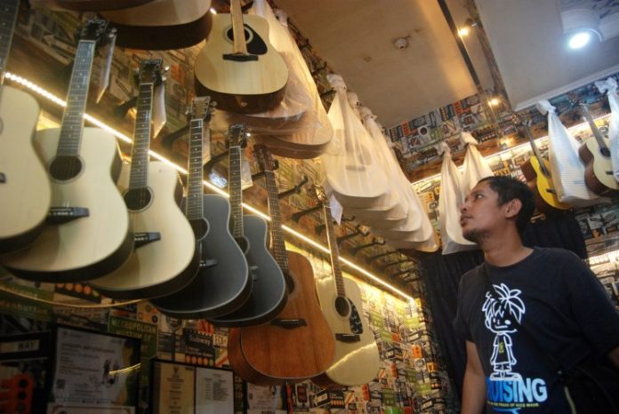 Pengunjung tengah melihat gitar di salah satu toko penjual gitar di Medan
