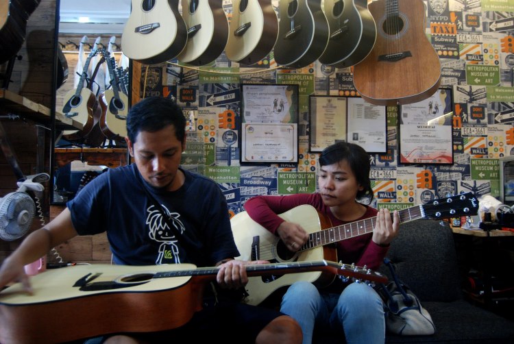 Pengunjung tengah mencoba gitar yang hendak dibeli di Kota Medan
